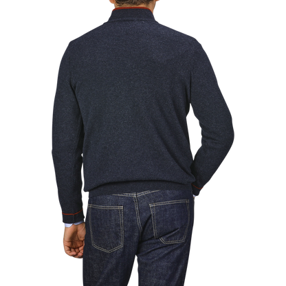 A person wearing the Fedeli Dark Blue Wool Cashmere 1/4 Zip Sweater and blue jeans is viewed from the back against a plain gray background. Their left hand is resting on their hip, showcasing the cozy wool-cashmere blend of their top.
