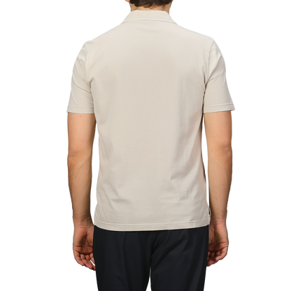 A person wearing a Fedeli Light Beige Organic Cotton Capri Collar Polo Shirt is paired with black pants, standing against a gray background.