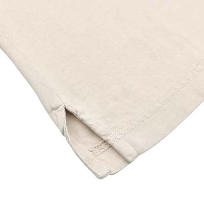 A close-up of the Light Beige Organic Cotton Capri Collar Polo Shirt by Fedeli highlights a corner with a side slit and reinforced stitching, exuding a casual summer vibe.