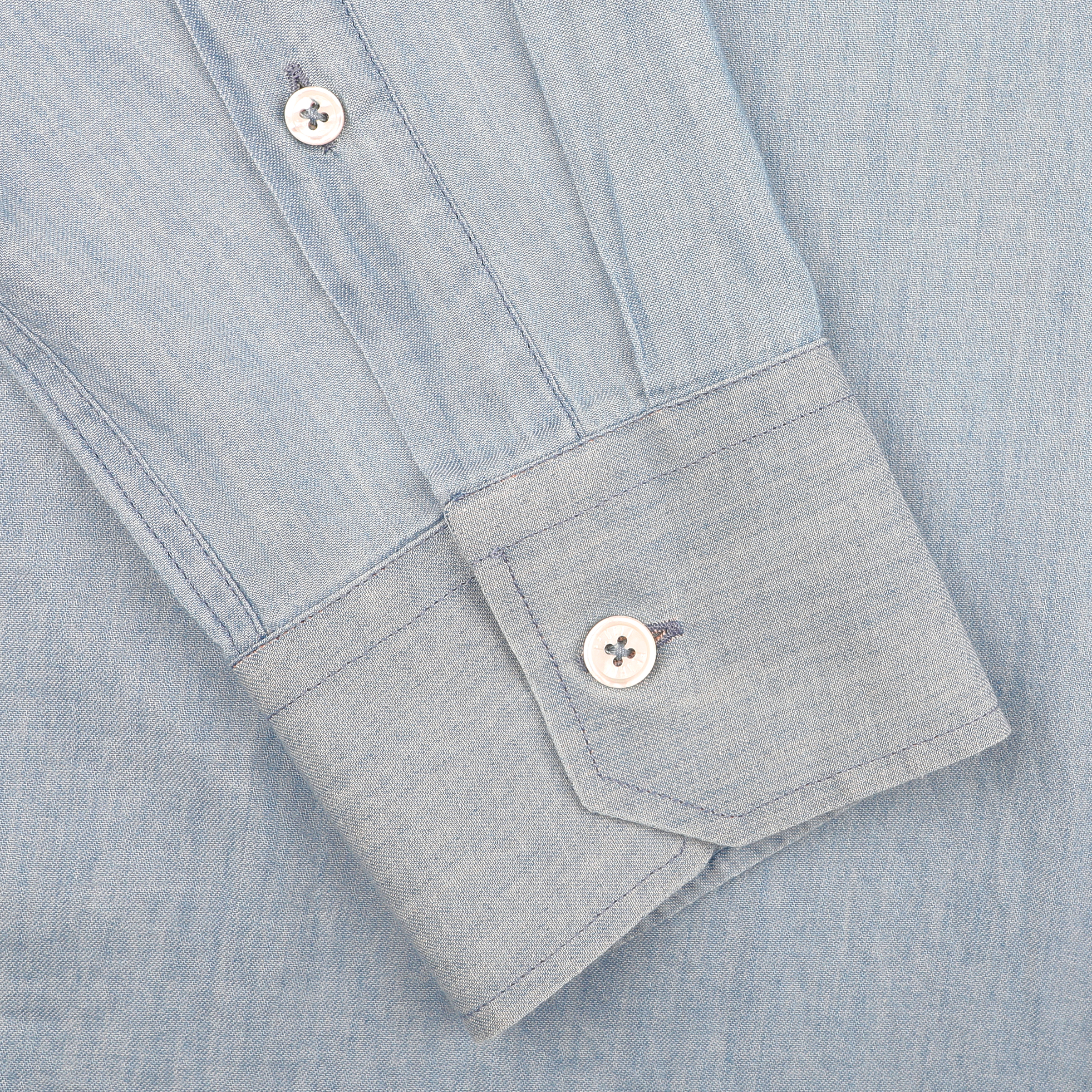 A light blue cotton denim shirt by Fedeli, featuring a slim fit design with casual shirt cuffs and two white buttons, is buttoned and lying flat.
