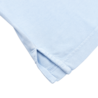 Close-up of the corner of a Fedeli Light Blue Organic Cotton Capri Collar Polo Shirt, made from organic Giza cotton, featuring fine stitching and a small side slit on a white background. Ideal for luxury casual-wear fans.