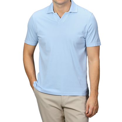 A person showcases a stylish look with Fedeli's Light Blue Organic Cotton Capri Collar Polo Shirt paired with beige pants, standing against a gray background with one hand in their pocket.
