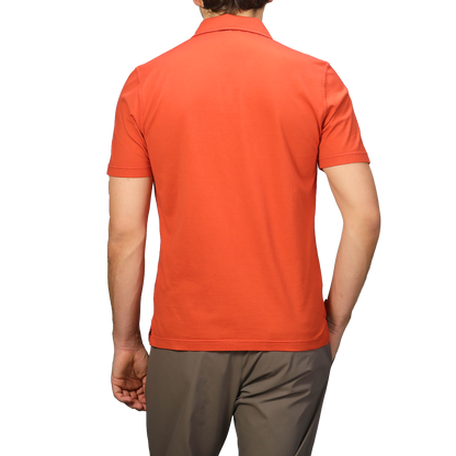 Seen from behind, a person wears an Orange Organic Cotton Capri Collar Polo Shirt by Fedeli and brown pants, epitomizing luxury casualwear.