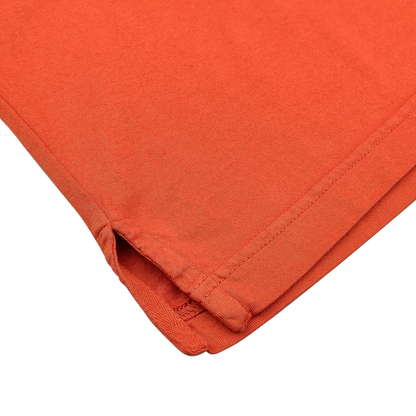 Close-up of the corner of Fedeli's Orange Organic Cotton Capri Collar Polo Shirt, highlighting detailed stitching and a small hem slit. Made from organic Giza cotton, it represents luxury casual-wear at its finest.