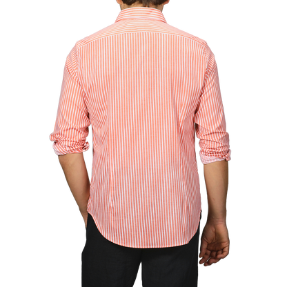 Person wearing an orange and white striped long-sleeve beach shirt from Fedeli, made from cotton stretch fabric, viewed from the back.