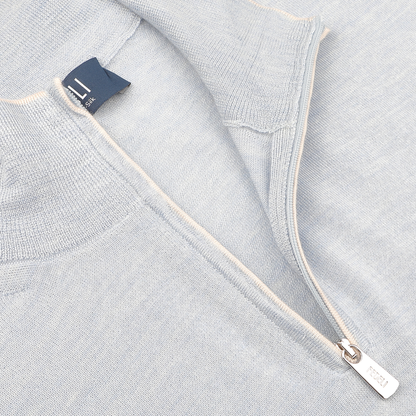 Close-up of Fedeli's Sky Blue Cashmere Silk 1/4 Zip Sweater, showcasing a small metal pull tab and a visible clothing tag.