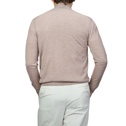 A person is seen from the back, wearing a Fedeli Taupe Beige Cashmere Silk 1/4 Zip Sweater and white pants.