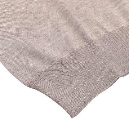 A close-up of the Taupe Beige Cashmere Silk 1/4 Zip Sweater by Fedeli reveals its luxurious cashmere-silk blend fabric with a ribbed hem.