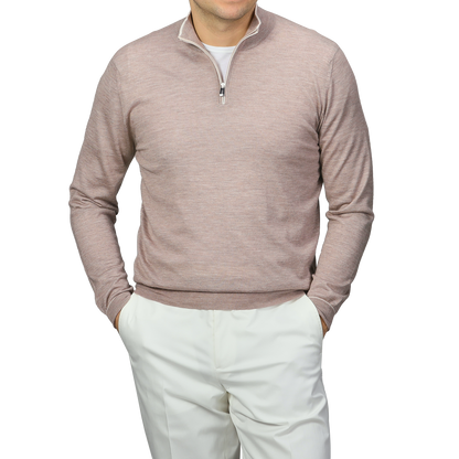A person in a Fedeli Taupe Beige Cashmere Silk 1/4 Zip Sweater over a white shirt with white pants stands hands-in-pockets against a gray background.
