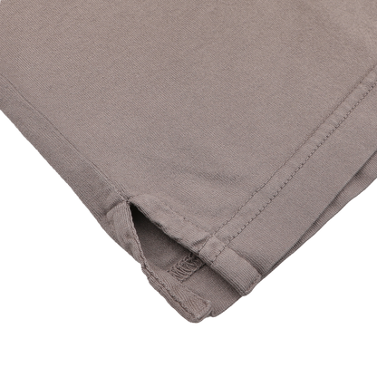 Close-up of the hem of a Taupe Beige Organic Cotton LS Polo Shirt by Fedeli, featuring a small side slit and visible stitching on a white background, showcasing the elegance of luxury casual-wear.