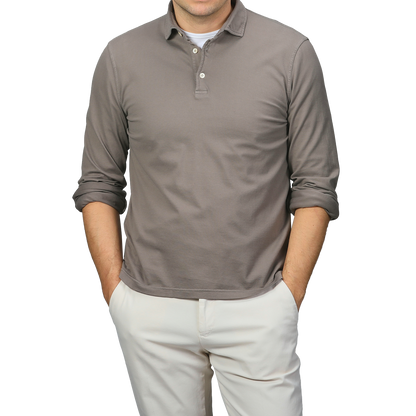 A person in a Fedeli Taupe Beige Organic Cotton LS Polo Shirt and light pants stands with hands in pockets, exuding effortless elegance.