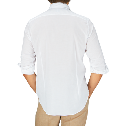 A person viewed from behind wearing a Fedeli white cotton-stretch beach shirt and beige trousers.