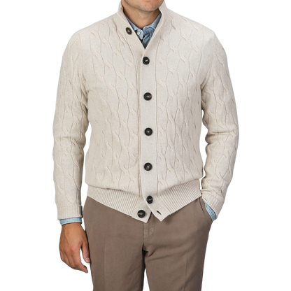 A person is wearing a Filippo de Laurentiis Cream Wool Cashmere Cableknit Button Cardigan over a blue shirt, paired with brown pants, standing against a plain background.