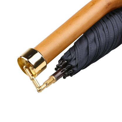 Close-up of a Fox Umbrellas' Navy Blue Malacca Handle Packable Umbrella, handmade in England, showcasing a wooden curved handle with stylish gold accents.