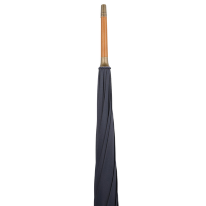The Fox Umbrellas' Navy Blue Malacca Handle Packable Umbrella, handmade in England, features a sleek navy blue canopy with a crook-handled wooden grip, standing upright against a white background.