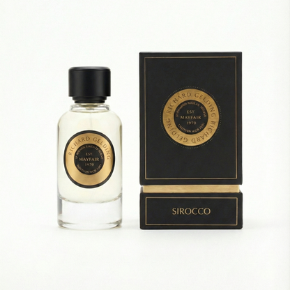 A clear glass bottle with a black cap and gold-black label stands next to a box labeled "Richard Gelding Sirocco EdP 100ml." This oriental scent by Richard Gelding promises long-lasting fragrance. Photo on white background. , available at Richard Gelding Mayfair