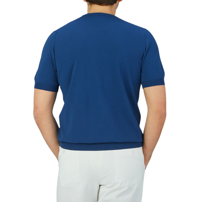 The back view of a man wearing a lightweight, Gran Sasso Indigo Blue Knitted Organic Cotton T-Shirt and white pants.