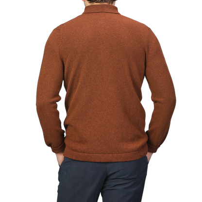 A person is seen from the back against a plain background, wearing a Burnt Orange Virgin Wool LS Polo Shirt by Gran Sasso paired with dark pants.