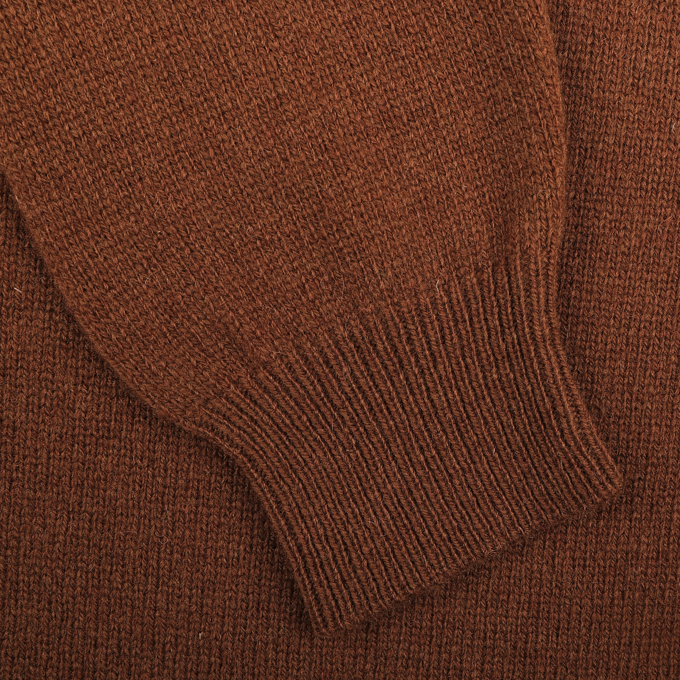 Close-up of a burnt orange virgin wool long sleeve polo shirt sleeve by Gran Sasso, featuring a ribbed cuff that highlights the detailed knitting texture.