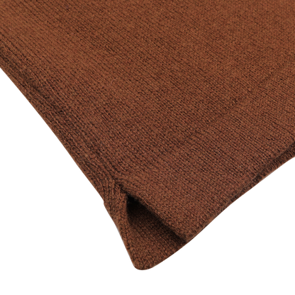 Close-up of a brown knitted fabric, evocative of the intricate texture and corner stitching found on the Gran Sasso Burnt Orange Virgin Wool LS Polo Shirt, set against a white background.