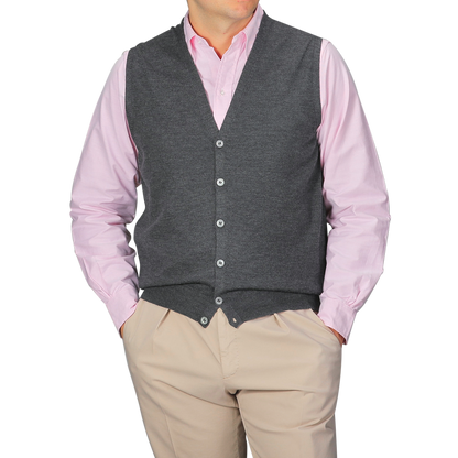 A person layers a light pink button-up shirt with the Gran Sasso Charcoal Extra Fine Merino Wool Vest and beige pants, hands in their pockets.