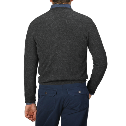 A person is shown from the back against a plain background, wearing a Charcoal Grey Cashmere V-Neck Sweater by Gran Sasso and dark blue pants, both meticulously crafted from pure cashmere fibers.