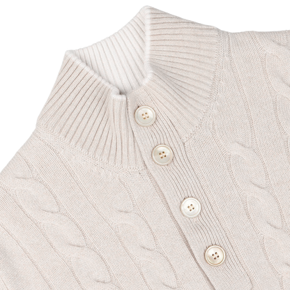 Close-up of a cream pure cashmere quarter button sweater featuring a cable-knit design, high ribbed collar, and three vertically aligned beige buttons in the front. Crafted with impeccable care, this Gran Sasso creation exudes timeless elegance.