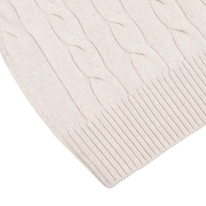 A close-up view of a Cream Pure Cashmere Quarter Button Sweater by Gran Sasso, featuring ribbed hem detailing.
