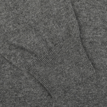 Close-up of a Gran Sasso Grey Melange Cashmere 1/4 Zip Sweater, focusing on a ribbed cuff. The texture of the material is visible, showing fine stitching and a consistent knitting pattern. This premium knitwear exhibits exceptional craftsmanship that's evident in every detail.