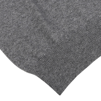 Close-up image of the corner of a Grey Melange Cashmere 1/4 Zip Sweater by Gran Sasso, showcasing its luxurious wool knitted fabric with a ribbed texture, reminiscent of premium knitwear, set against a white background.