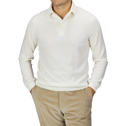 A man wearing a Gran Sasso Ivory Merino Wool One-Piece Collar Polo Shirt with beige corduroy pants, hands in his pockets, stands against a plain background.
