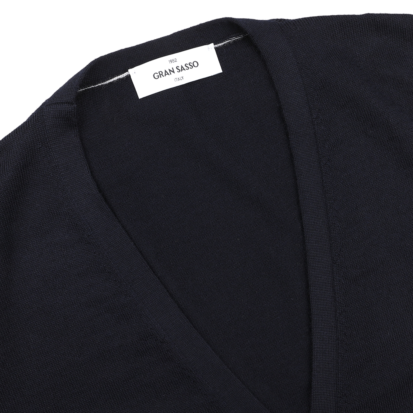 Close-up of a navy blue extra fine merino wool vest from Gran Sasso, with a white "GRAN SASSO 1952" label sewn into the collar—ideal for layering under a sleeveless cardigan.