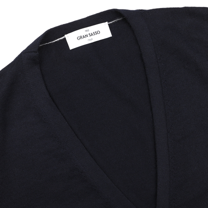 Close-up of a navy blue extra fine merino wool vest from Gran Sasso, with a white "GRAN SASSO 1952" label sewn into the collar—ideal for layering under a sleeveless cardigan.