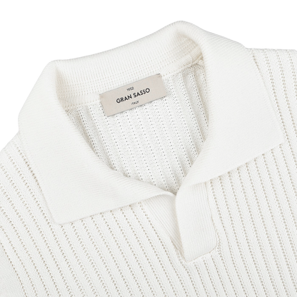 Close-up of an off-white, slim fit ribbed knit polo shirt with a collar and an inner label reading "Gran Sasso," made from soft organic cotton for unmatched comfort.
