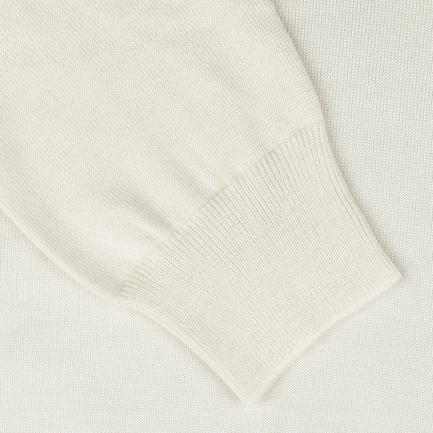 Close-up of the Gran Sasso Off White Extra Fine Merino Rollneck sweater sleeve, featuring a ribbed cuff on a matching textured surface.