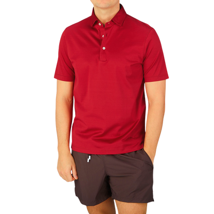 A man wearing a Gran Sasso Raspberry Red Cotton Filo Scozia polo shirt and shorts.