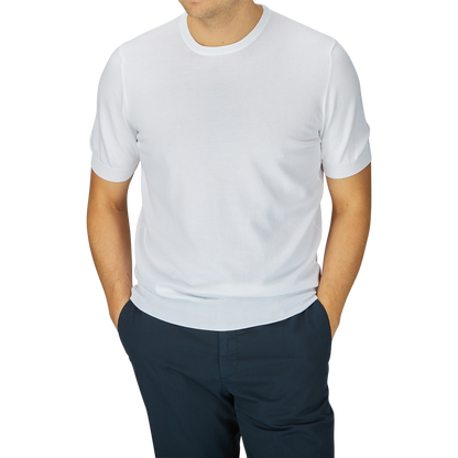 A man wearing a Gran Sasso white organic cotton knitted t-shirt and navy blue pants, standing with his arms slightly away from his sides.