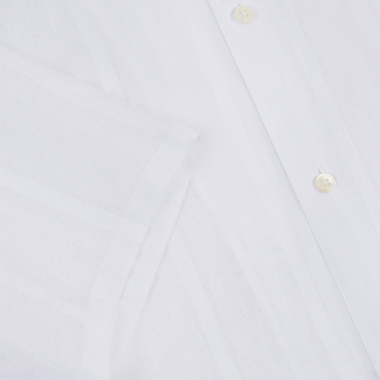 Close-up of the Maurizio Baldassari White Linen Short Sleeve Bowling Shirt, highlighting its white buttons, neatly folded sleeve, and subtly sheer, breathable linen fabric with a visible weave pattern. , available at Richard Gelding Mayfair