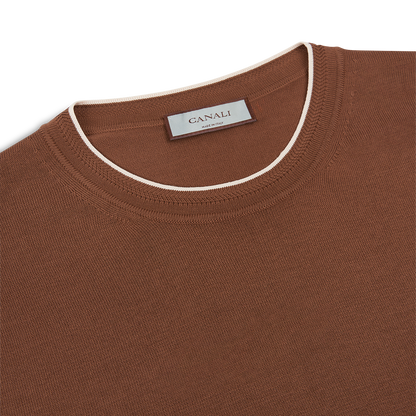 A close-up of a brown Canali Giza Cotton T-shirt with white contrast piping along the neckline. The texture and a Canali label at the inside back, showing "Canali" and "Made in Italy," are visible. , available at Richard Gelding Mayfair