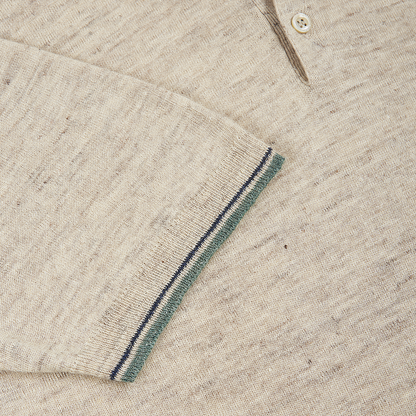 A close-up of the Altea Beige Cotton/Linen Polo shows the sleeve cuff with thin navy and green stripes near the edge, a visible button and placket, and a soft, speckled texture as it overlaps the torso. , available at Richard Gelding Mayfair