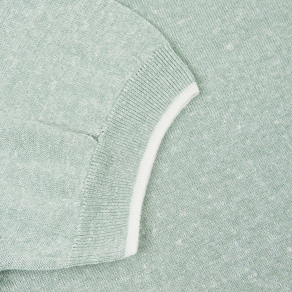 Close-up of the Fedeli Green Melange Linen Cotton T-Shirt. The light green, short sleeve is folded, revealing ribbed white trim at the cuff. The soft fabric features a subtle heathered texture with interwoven white fibers. , available at Richard Gelding Mayfair