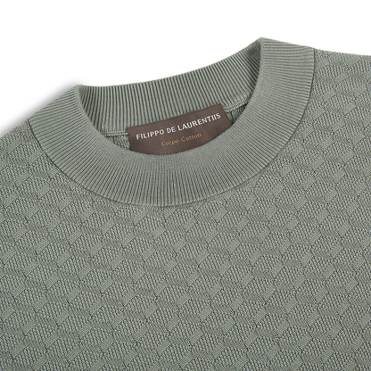 Close-up of the Filippo de Laurentiis Sage 3D Weave Crepe Cotton T-Shirt, featuring a light sage green textured crewneck and subtle geometric pattern. The brown neck label displays the brand name and "Crepe Cotton" in white. , available at Richard Gelding Mayfair