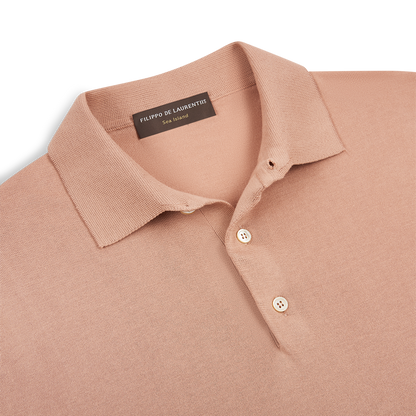 A close-up of a Peach Sea Island Cotton Polo Shirt by Filippo de Laurentiis, featuring a classic collar and two white buttons. The soft, finely textured fabric is laid flat against a white background. , available at Richard Gelding Mayfair