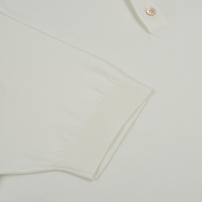 A close-up of the Filippo de Laurentiis Cream Sea Island Cotton Polo Shirt shows the ribbed short sleeve cuff, beige button on the placket, and its subtly textured knit. , available at Richard Gelding Mayfair