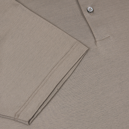 A close-up of the Gran Sasso Taupe Filo Scozia Polo highlights a folded sleeve with visible stitching and part of the front placket with a single button, showcasing the shirt’s smooth, subtly textured fabric. , available at Richard Gelding Mayfair