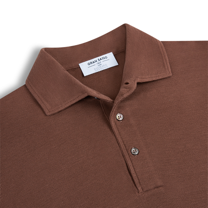 A close-up of a brown Gran Sasso Silk Pique Short Sleeve Polo features textured fabric, a pointed collar, two buttons, and a visible white label inside the collar showing the brand name and size. , available at Richard Gelding Mayfair