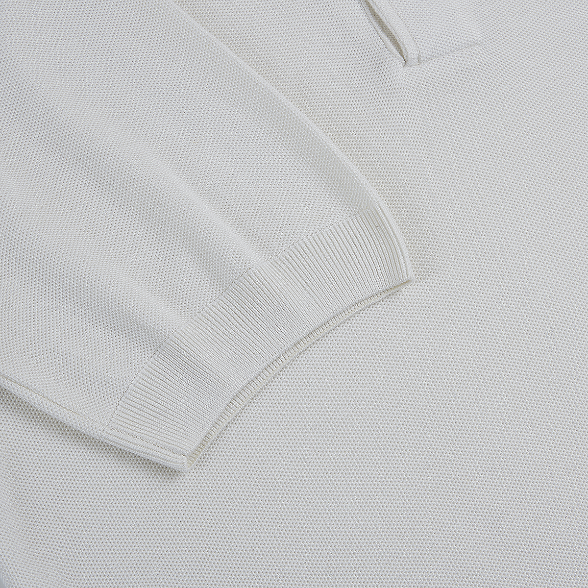 Close-up of the Gran Sasso White Silk Pique Polo, highlighting the soft, fine textured knit fabric and ribbed cuff on the long sleeve. The material features uniform, small bumps throughout for a refined look. , available at Richard Gelding Mayfair