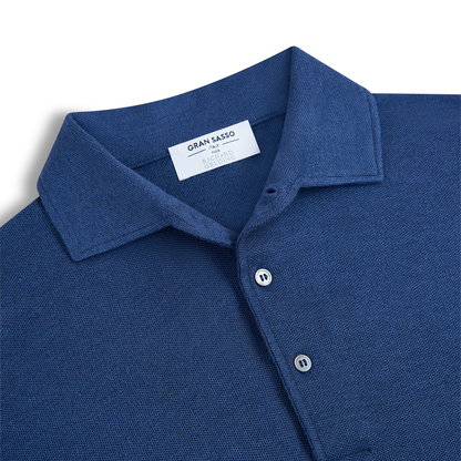 Close-up of a Gran Sasso Navy Blue Silk Pique Polo with a pointed collar and two buttons. A white label inside the collar displays the brand name. The shirt is laid flat on a white background. , available at Richard Gelding Mayfair