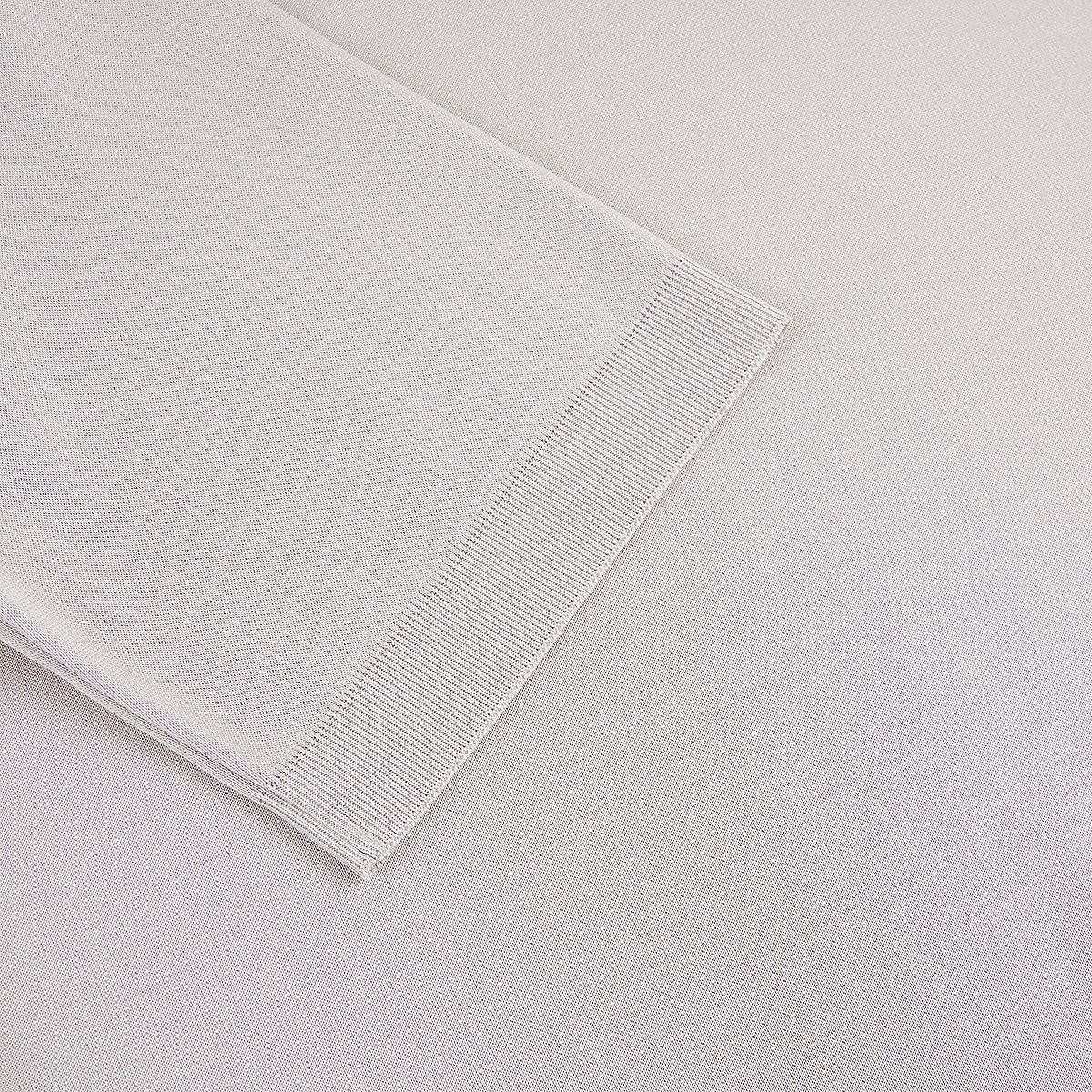 A close-up of the Herno Light Grey Cotton Knitted Open Neck Polo shows fine, even stitching and a ribbed hem, with subtle shadows highlighting the texture and weave of the premium fabric. , available at Richard Gelding Mayfair