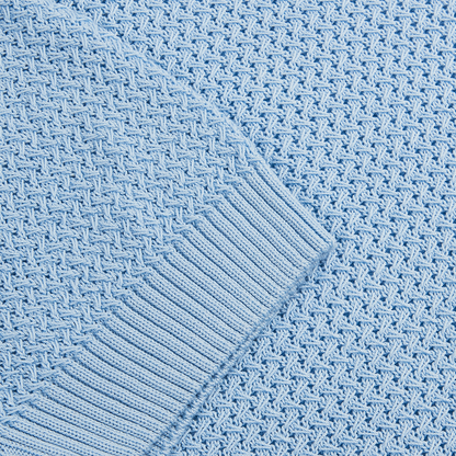 Close-up of the Sky Blue Open Weave Skipper Polo by Filippo de Laurentiis, showing its textured diamond knit and contrasting ribbed hem. The lighting emphasizes the intricate details of this stylish fabric. , available at Richard Gelding Mayfair